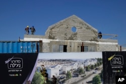 FILE - Men work on a new housing project in the West Bank settlement of Naale, Jan. 1, 2019.