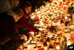 FILE - Candles are placed outside the French embassy in Vilnius, Lithuania, for the victims in Friday's attacks in Paris, Nov. 14, 2015.