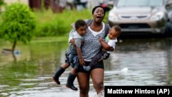 Majka sa decom pokušava da se probije kroz poplavljenu ulicu u Nju Orleansu