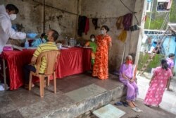 Seorang petugas kesehatan (kiri) mengenakan Alat Pelindung Diri (APD), melakukan tes swab untuk Covid-19 di Mumbai, 19 Agustus 2020. (Foto: INDRANIL MUKHERJEE / AFP)