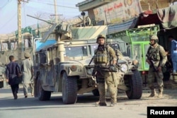 Afghan security forces keep watch in front of their armoured vehicle in Kunduz city, Afghanistan, Oct. 4, 2016.
