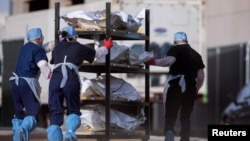 រូបឯកសារ៖ បុគ្គលិក​​ការិយាល័យ​​អ្នក​ពិគ្រោះជំងឺ​នៃ​សង្កាត់​ El Paso រុញ​​សាកសព ដែលត្រូវ​បាន​គេ​​ច្រក​ថង់ ដោយ​មាន​ស្លាកសញ្ញា​សរសេរ​ថា កូវីដ ចេញ​ពី​ទូទឹកកក ក្នុង​អំឡុងពេល​ដែល​មាន​ការ​ផ្ទុះ​រាតត្បាត​ជំងឺ​កូវីដ១៩ ក្រុង El Paso រដ្ឋ Texas ថ្ងៃទី២៣ ខែវិច្ឆិកា ឆ្នាំ២០២០។ 