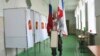 A polling station official with Russian national and Crimea flags is prepared for the 2018 Russian presidential election, in Simferopol, Crimea, March 17, 2018.