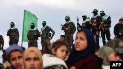 ນັກຮົບແລະຜູ້ຄຸ້ມຄອງຂອງກຸ່ມຮາມາສໃນປາເລສໄຕນ໌ເຕົ້າໂຮມກັນທີ່ຈຸດສົ່ງມອບສົບໂຕປະກັນຊາວອິສແອລ 4 ຄົນໃນເມືອງຄານຍູນິສທາງພາກໃຕ້ຂອງເຂດກາຊາເມື່ອວັນທີ 20 ກຸມພາ 2025. 