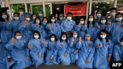 Staf medis memberi hormat tiga jari dengan pita merah pada seragam mereka di Rumah Sakit Umum Yangon di Yangon pada 3 Februari 2021 ketika seruan untuk melakukan pembangkangan semakin marak menyusul kudeta militer yang menahan Aung San Suu Kyi. (Foto: AFP)