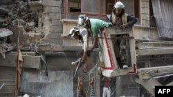 Tim penyelamat Suriah menyerahkan anak perempuan kepada seorang warga setelah berhasil diselamatkan dari runtuhan gedung setelah serangan udara di kawasan yang dikuasai pemberontak di Al-Shaar, Aleppo, 27 September 2016. 