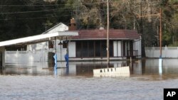 A Merry Christmas sign is mostly submerged by floodwaters from the Pea River, Dec. 26, 2015 in Elba, Ala. 