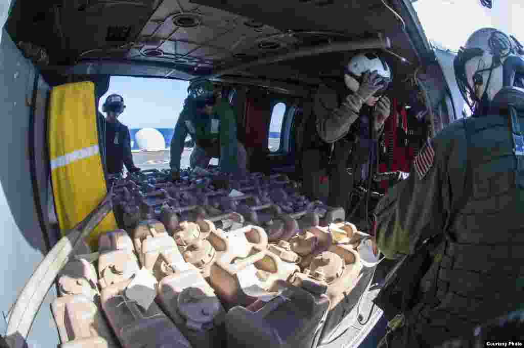 Sailors aboard the U.S. Navy's forward-deployed aircraft carrier USS George Washington load containers of water onto an MH-60S Seahawk for the Philippines, Nov. 15. 2013. (U.S. Navy) 
