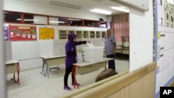 Bosnian woman, shown in a mirror, cast his vote at poling station in Sarajevo, Bosnia, on Sunday, Oct. 7, 2018.