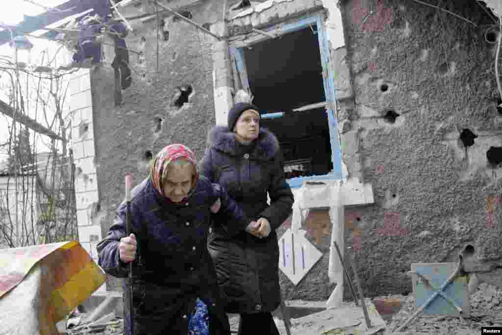 People walk outside a house, which according to locals, was recently damaged by shelling, in Donetsk, Feb. 3, 2015.