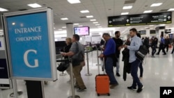 Passengers wait at the security entrance to Concourse G at Miami International Airport in Miami, Jan. 11, 2019.
