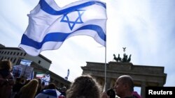 Ljudi mašu izraelskim zastavama na skupu u znak solidarnosti sa Izraelom u Berlinu, poslije napada Irana na Izrael dronovima i raketama, 14. aprila 2024. (Foto: Reuters/Annegret Hilse)
