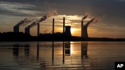  In this June, 3, 2017, file photo, the sun sets behind Georgia Power's coal-fired Plant Scherer, one of the nation's top carbon dioxide emitters, in Juliette, Ga. (AP Photo/Branden Camp, File)