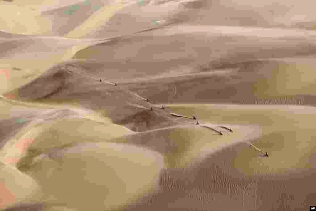 Racers ride their motorcycles across the sand during the Dakar Rally in Pisco, Peru, on January 16, 2019. (AP Photo/Ricardo Mazalan)