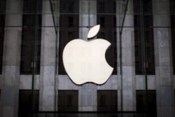 FILE - An Apple logo hangs above the entrance to the Apple Store on Fifth Avenue in the Manhattan borough of New York City,  July 21, 2015.
