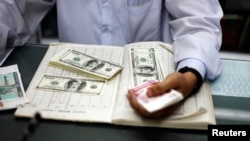 Myanmar man counts US dollars and Myanmar kyats