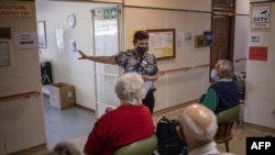 Home manager Theresa Swart, center, explains to elderly guests of the retirement home how the Pfizer vaccine works during a vaccination run near Klerksdorp, South Africa on May 19, 2021.