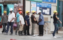 FILE - Workers are searched by security guards as they leave a construction site in a Kuala Lumpur suburb, Malaysia, March 23, 2010.