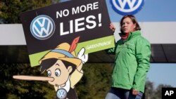 An activist with the environmental group Greenpeace protests Volkswagen emissions rigging. She stands outside a VW factory in Wolfsburg, Germany, Sept. 25, 2015.