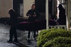 A police officer watches as a body is taken from the Gold Spa massage parlor after a shooting, March 16, 2021, in Atlanta, Georgia.