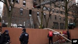 Firefighters and NYPD officers work outside an apartment building after a fire in the Bronx, in New York City, Jan. 9, 2022.