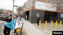 Emergency Medical Technicians move a patient while wearing personal protective equipment outside of Elmhurst Hospital during the ongoing outbreak of the coronavirus disease (COVID-19) in the Queens borough of New York, April 20, 2020.