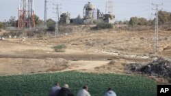 Warga duduk di depan menara pengawasan militer Israel sambil memperhatikan Israel mencari lima militan Palestina yang tewas di terowongan yang dihancurkan Israel dekat perbatasan Khan Younis, jalur Gaza, Jumat, 3 November 2017.