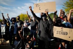 FILE - Protesters hold their fists in the air during a rally in Las Vegas against police brutality sparked by the death of George Floyd, June 5, 2020.