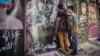 Young Lebanese peer through a gap in the wall, which was erected Monday in Beirut in the wake of clashes with protesters over the weekend. (Credit: John Owens/VOA)