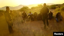 U.S. Border Patrol agents detain migrants who attempted to cross the U.S.-Mexico border undetected in a desert area outside Sunland Park, New Mexico, on June 23 2023.