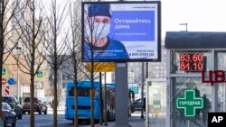An electronic billboard showing a doctor wearing a protective mask, with the words next to him reading "Stay home; it will save a life," is seen in a street in Moscow, Russia, March 25, 2020. 