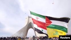 FILE - A man carries a giant banner comprising the flags of Iran, Syria, the Palestinian territories and Hezbollah, during a ceremony marking the 37th anniversary of the Islamic Revolution, in Tehran, Febr. 11, 2016. (REUTERS/Raheb Homavandi/TIMA)
