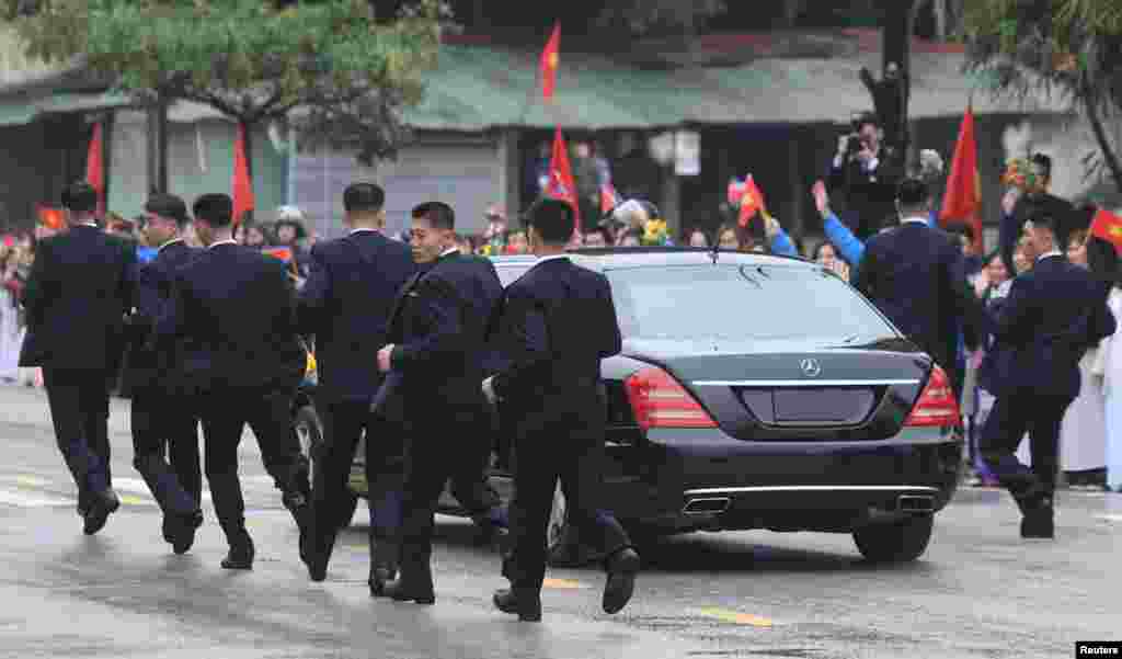 ក្រុម​អង្គរក្ស​កូរ៉េ​ខាងជើង​រត់​តាម​រថយន្ត​លីម៉ូស៊ីន​មួយ​ដែល​ជូន​មេដឹកនាំ​លោក​គីម ជុងអ៊ុន ខណ​ដែល​លោក​បាន​មកដល់​ទីក្រុង​ព្រំដែន​ជាមួយ​ចិន​ក្នុង​ទីក្រុង​ Dong Dang ប្រទេស​វៀតណាម។