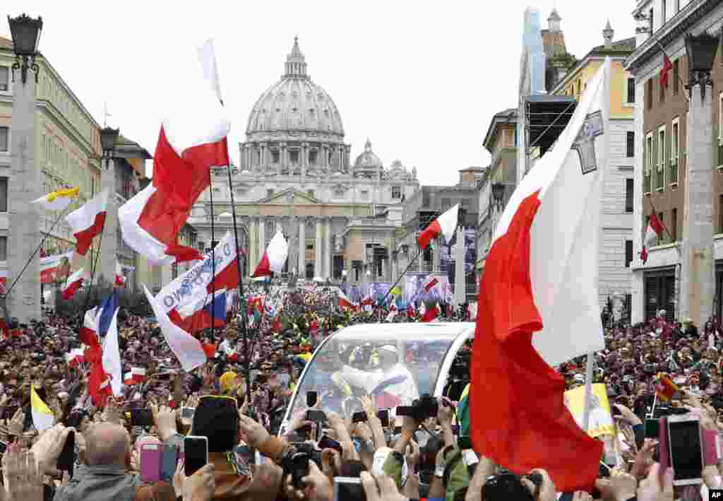 Pope Francis greets the faithful as he is driven through the crowd along Via della Conciliazione while celebrating the ceremony for the canonizations of Pope John XXIII and Pope John Paul II in St. Peter&#39;s Square, at the Vatican, April 27, 2014.