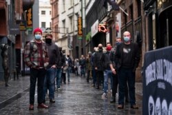FILE - Members of the entertainment industry stand on Matthew Street in Liverpool, England, Oct. 12, 2020, during a show of support for the hard-hit sector.