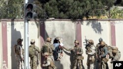 Pasukan keamanan Afghanistan menyelamatkan seorang pria dari kompleks stasiun televisi Shamshad di Kabul pasca serangan, 7 November 2017.