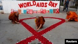 FILE - Buddhist monks light candles during an HIV/AIDS awareness campaign for World AIDS Day in Kolkata, India, Dec. 1, 2018. 