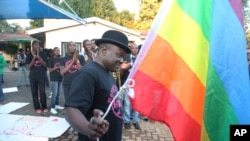 FILE - Samba Chesterfield, Director of Gays and Lesbians Association of Zimbabwe, prepares to hoist their official flag alongside the Zimbabwean flag during an event in Harare, Zimbabwe, May, 19, 2012. 