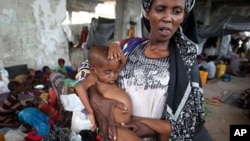 FILE - An internally displaced woman holds her malnourished son at a new settlement, Mogadishu, July 19, 2011.