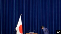 아베 신조 일본 총리가 14일 총리 관저에서 기자회견에 앞서 일장기를 향해 경례하고 있다.