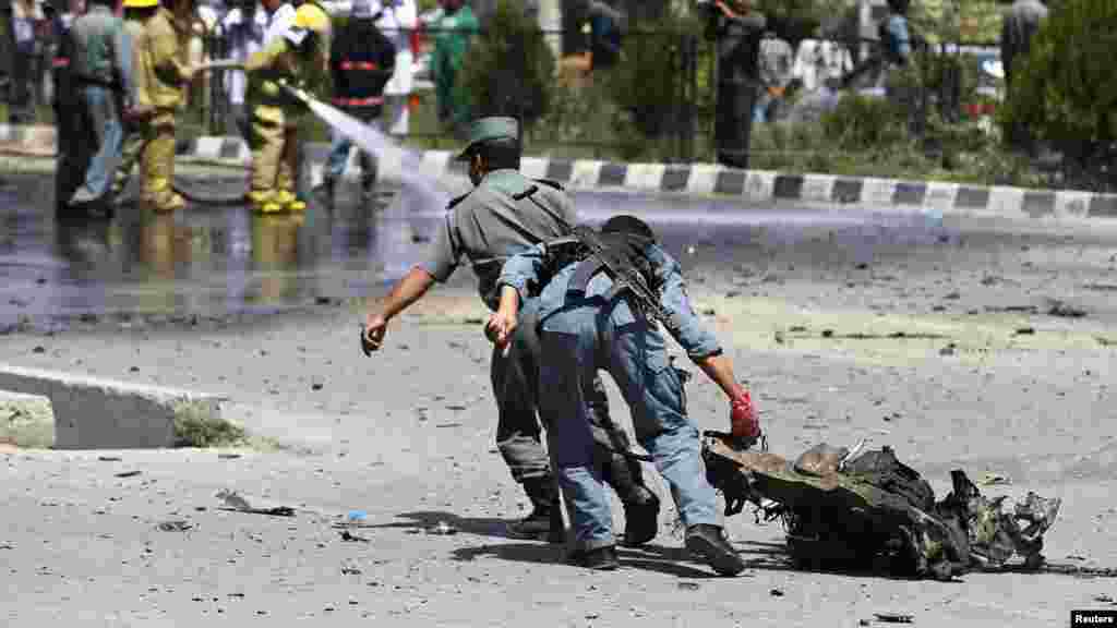Afghan policemen drag a piece of debris from a vehicle used in a suicide car bomb attack, in Kabul, Aug. 10, 2014. 