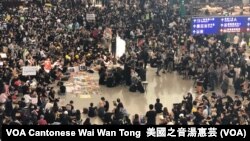 Aksi duduk di dalam Bandara Hong Kong, Jumat (26/7) memperingatkan para pengunjung soal demonstrasi yang baru-baru ini terjadi di kota tersebut. 