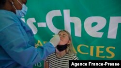 پس از کشف گونه «امیکرون» ویروس کرونا، کارکنان بهداشت در فرودگاه بین‌المللی ژوهانسبورگ، آفریقای جنوبی از مسافران تست کرونا می‌گیرند - ۶ آذر ۱۴۰۰