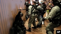 Riot police detain a protester, left lying on the ground, during a demonstration in Hong Kong, Dec. 25, 2019. 