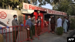 Afghan medical staff members stand at the entrance of a hospital as they wait to receive the victims of an explosion in Kabul, Oct. 3, 2021.