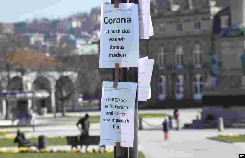 Signs reading &quot;Corona is also what we do out of it&quot; (top) and &quot;Imagine this is Corona and nobody looks at it panickly&quot; are seen on a pole in Stuttgart, southern Germany.