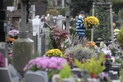 A man carries flowers in a cemetery in Strasbourg, eastern France on Nov. 1, 2020, during All Saint's day festivities.