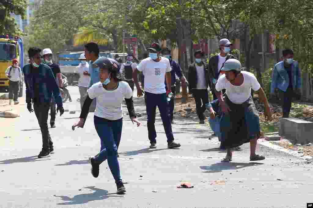 Protesters run as police fire tear gas during a protest against the military coup in Mandalay, Myanmar, Feb. 28, 2021.