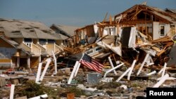 FILE - An American flag flies amongst rubble left in the aftermath of Hurricane Michael in Mexico Beach, Florida, Oct. 11, 2018.