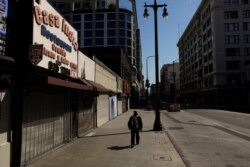 A man walks on a sidewalk lined with shuttered shops June 3, 2020, in downtown Los Angeles, as protests continue over the death of George Floyd on May 25 in Minneapolis.